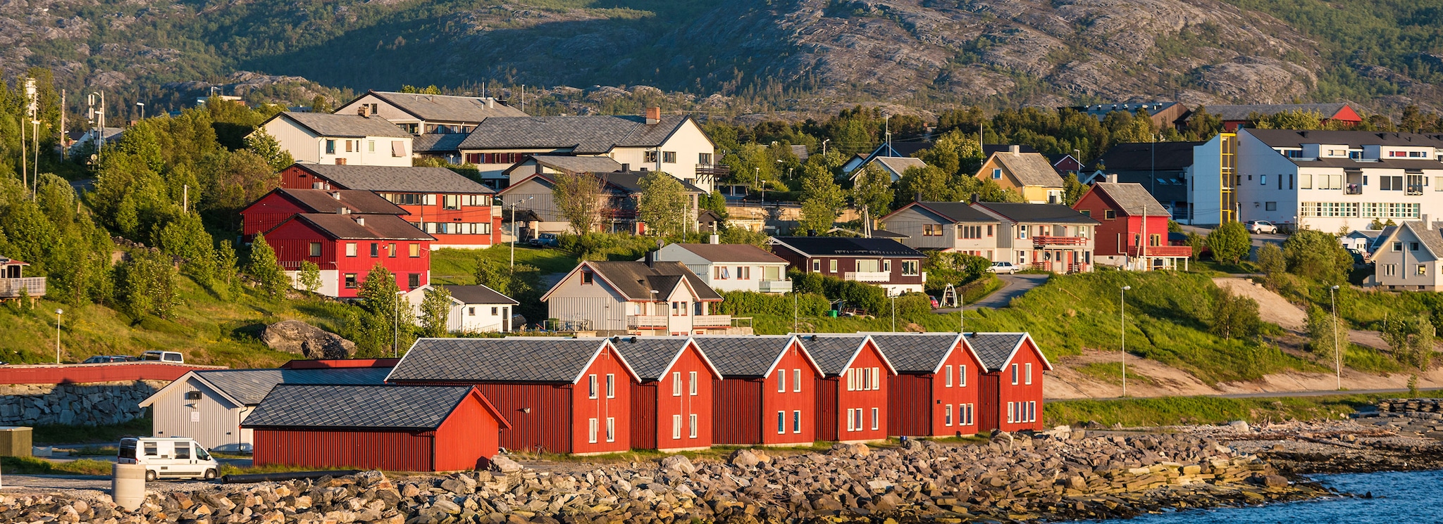 Red houses facades reflecting on the bay of Alta, Norway;