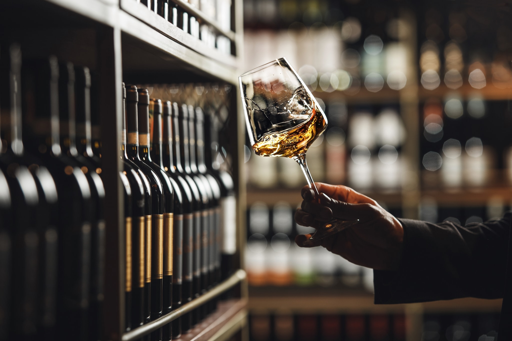 {"metadata_en_GB":{"alt-text":"Close-Up of Sommelier Tasting White Wine in Dimly Lit Cellar"}}